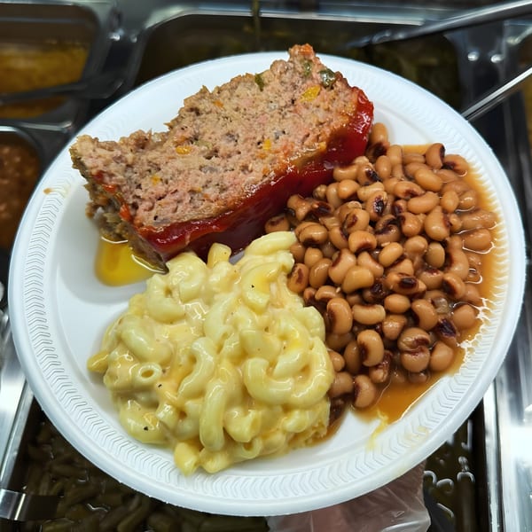 A southern meal with meatloaf, macaroni and cheese, and black-eyed peas on a white plate.