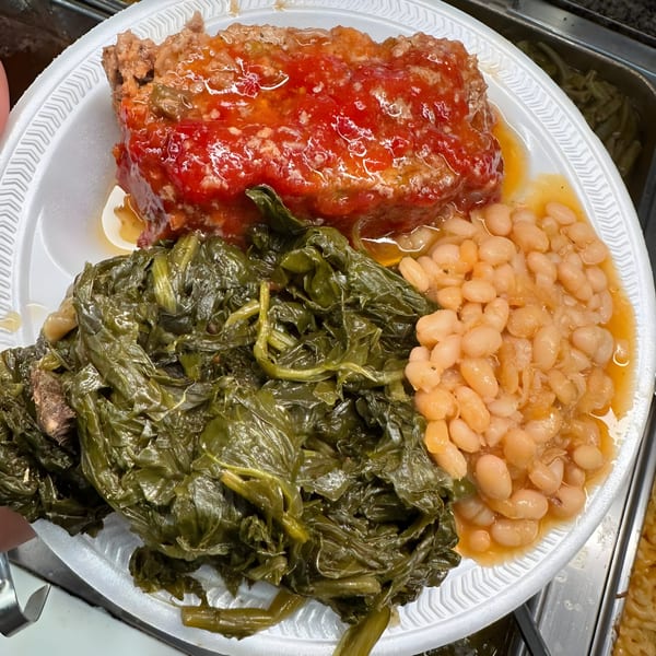 Southern meatloaf with tomato glaze, collard greens, and white beans on a white plate.